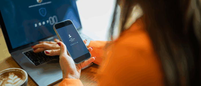 Woman holding a phone and looking at a laptop